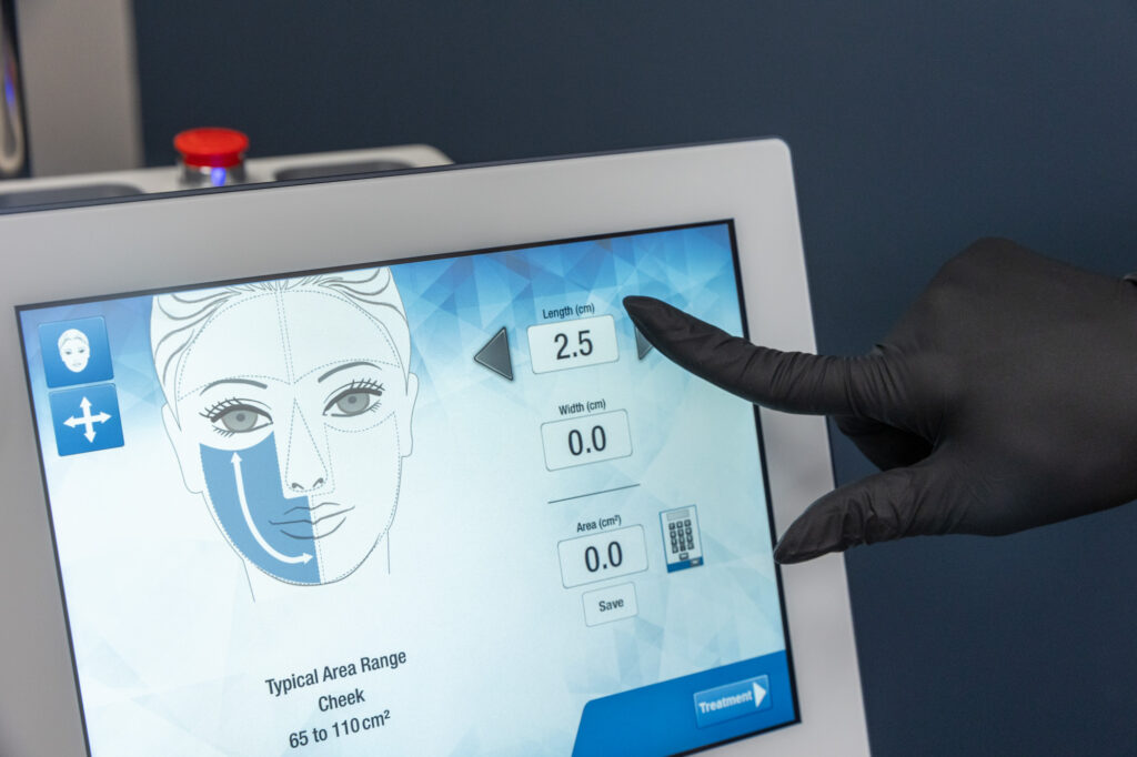 A provider wearing a black glove adjusts the settings on the Moxi laser, one of our advanced laser treatments near Cedar Hill, TX, that we can use year-round to promote a more youthful appearance.